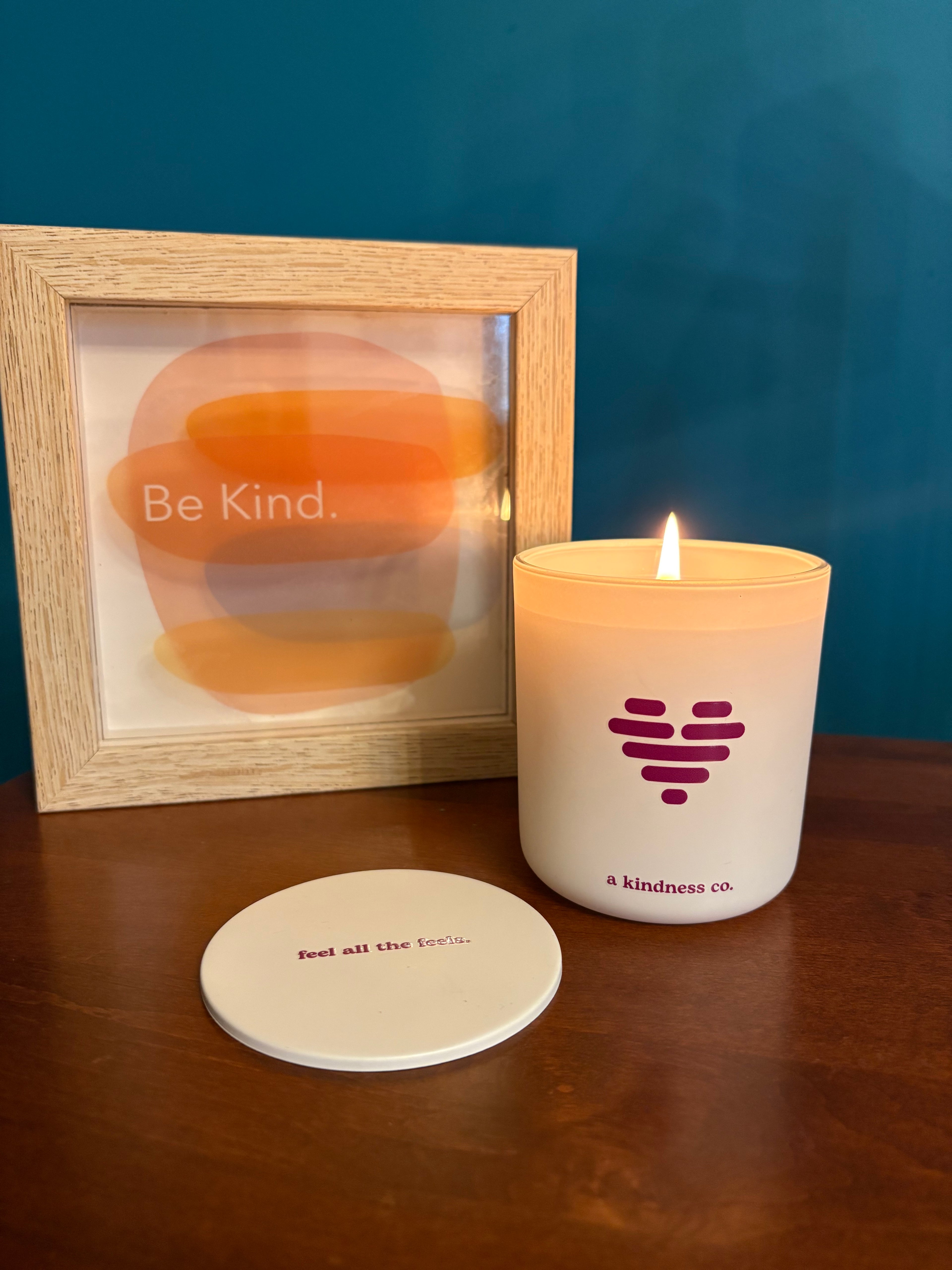 White candle jar with luv heart icon on front and lid with feel all the feels message with wooden be kind sign