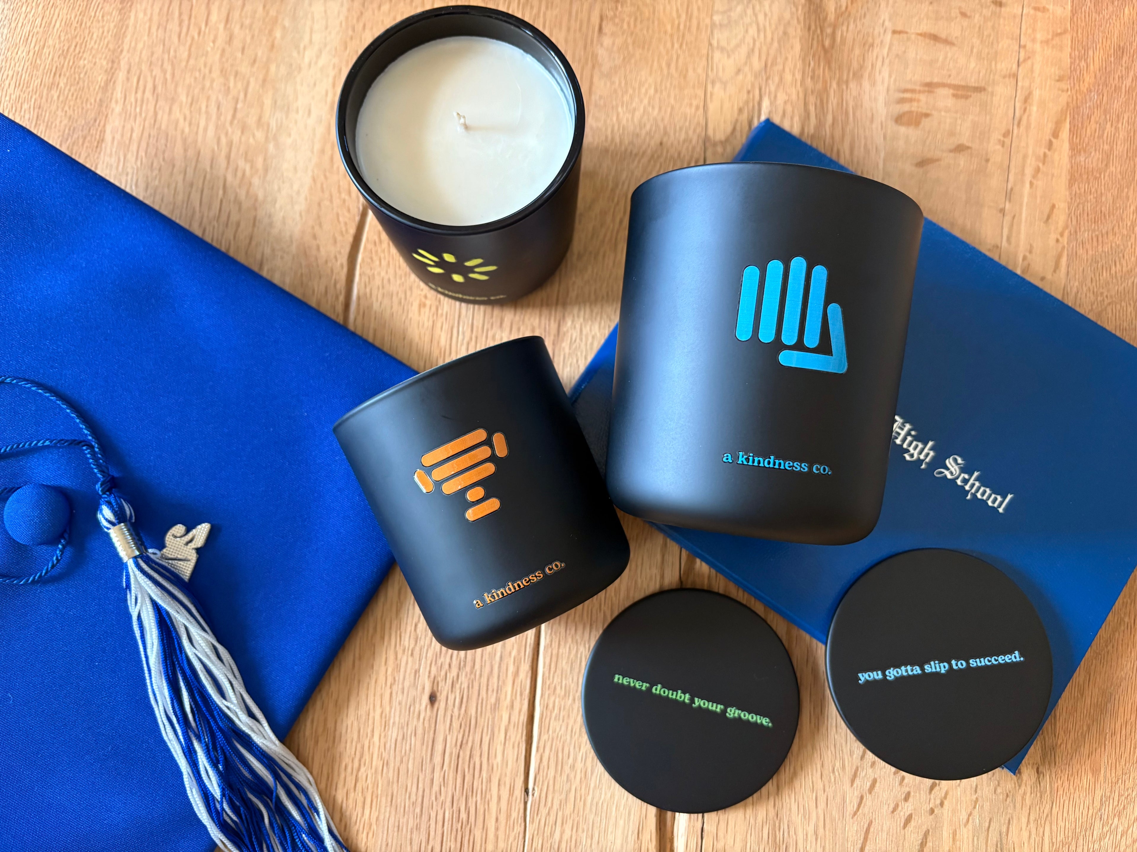 Graduation cap on table with A Kindness Co Candles